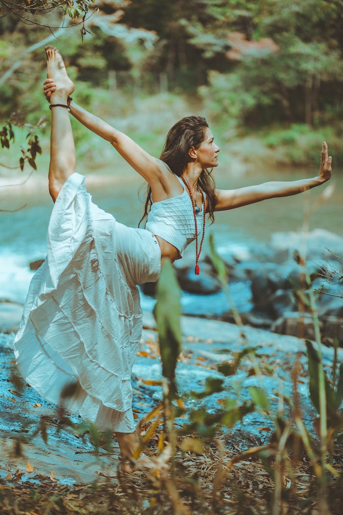 A serene scene of a woman practicing yoga by a picturesque river shore, embodying balance and tranquility.