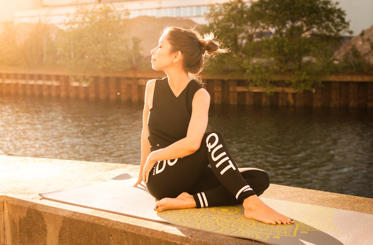 Woman practicing yoga at sunset by a serene river in Gamla Staden, Sweden.